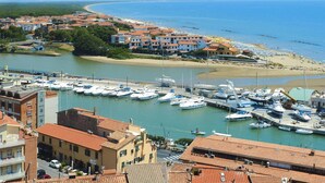 Un puerto deportivo con barcos amarrados, una playa y edificios con techos de tejas rojas.