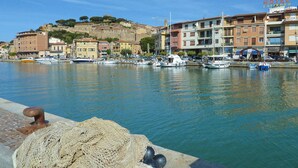 Un puerto deportivo con barcos, un hotel llamado "HOTEL LAFERNO" al fondo y un edificio histórico en la cima de una colina.