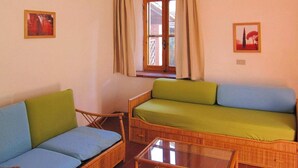 Una habitación con un sofá verde, un sofá azul y una mesa de centro de vidrio.