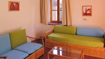 A room with a green sofa, a blue sofa, and a glass coffee table.