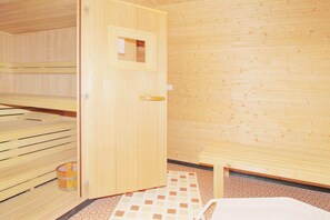 A sauna room with wooden benches, a door, and a patterned floor.