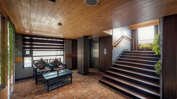 Un interior moderno con techo de madera, una escalera y un área de descanso con mesa y sillas.