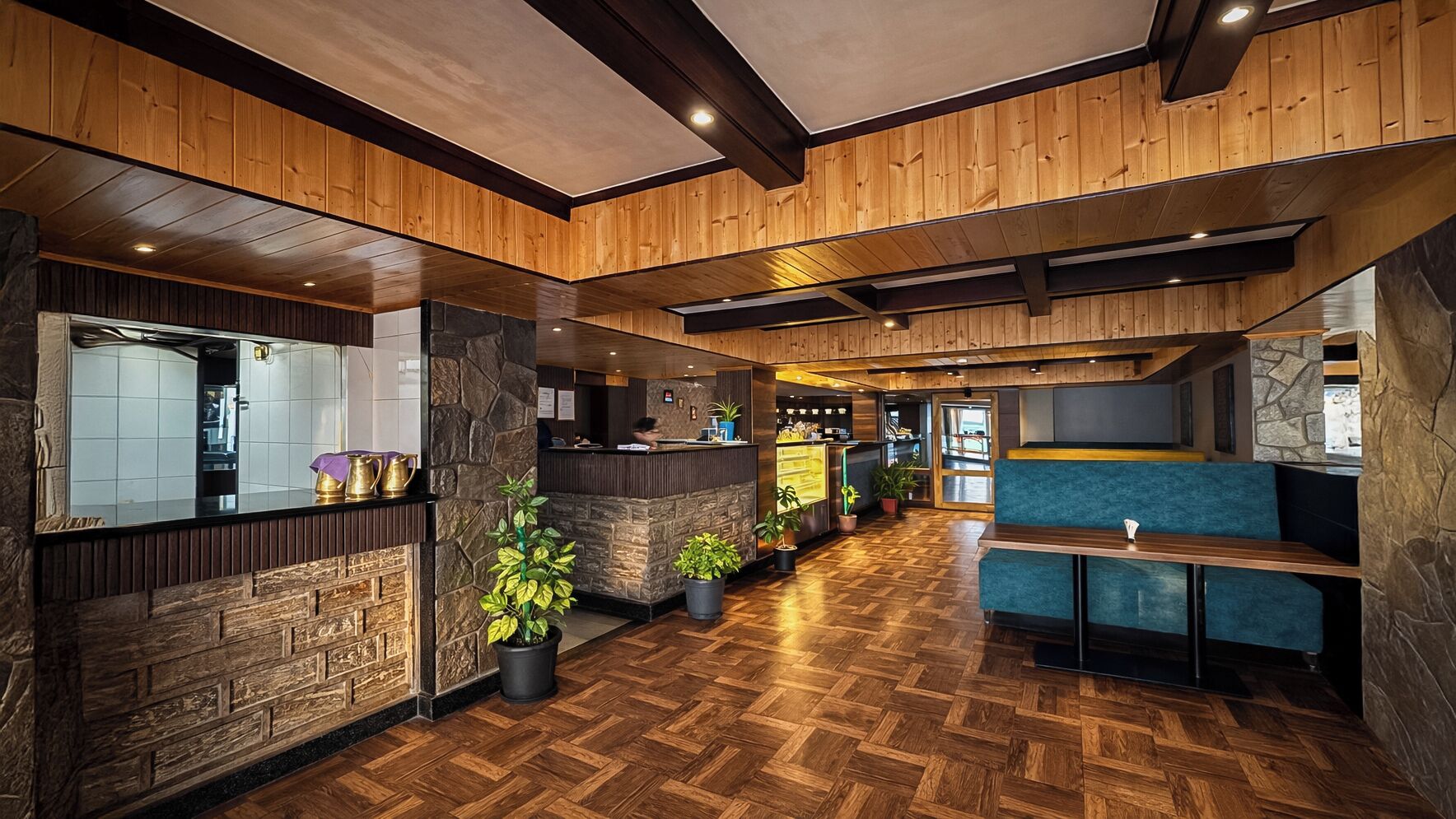 A reception area with a wooden floor, stone accents, and a seating area with blue upholstered benches.
