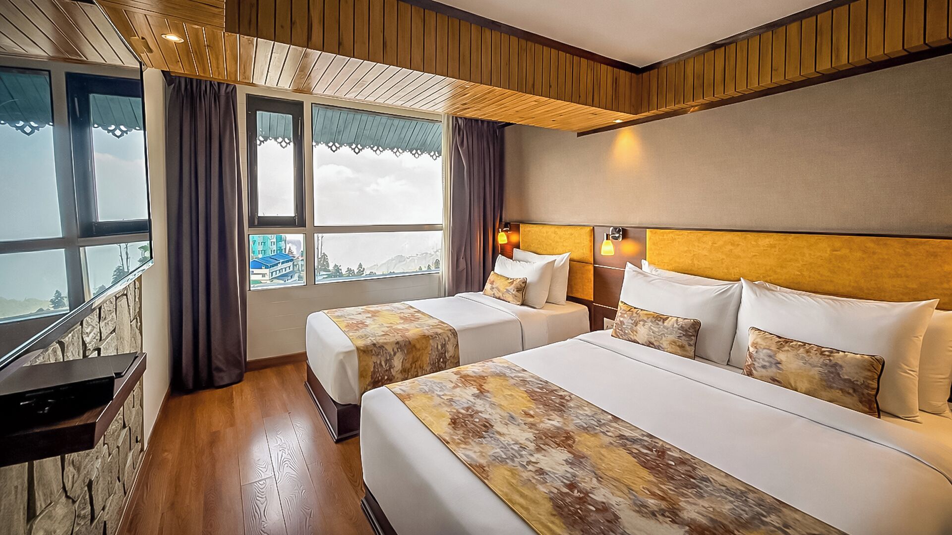 Une chambre d’hôtel avec deux lits, une vue sur la ville, un plafond en bois et un mur en pierre.