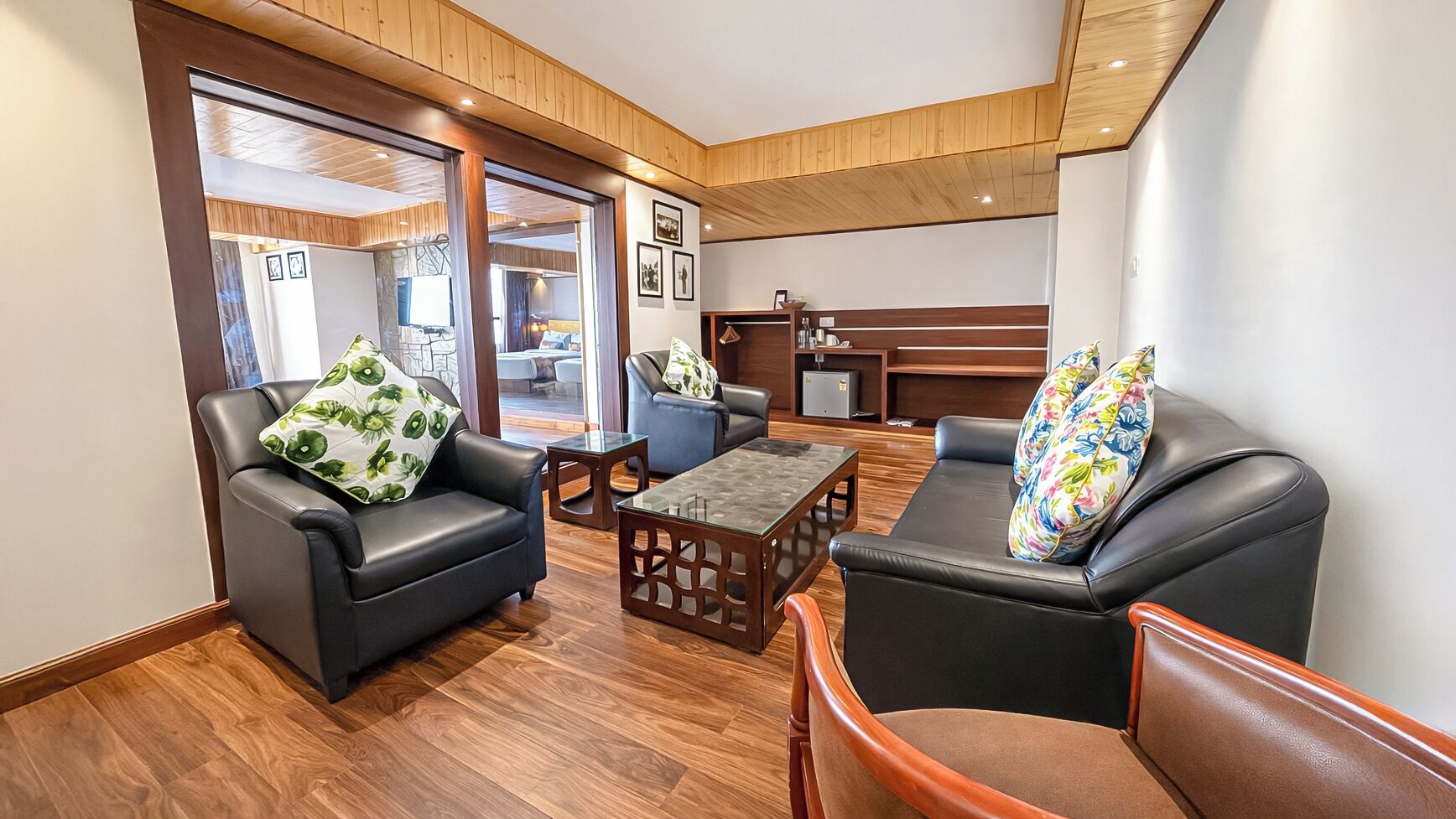 A modern living room with leather sofas, a glass coffee table, and wooden flooring.