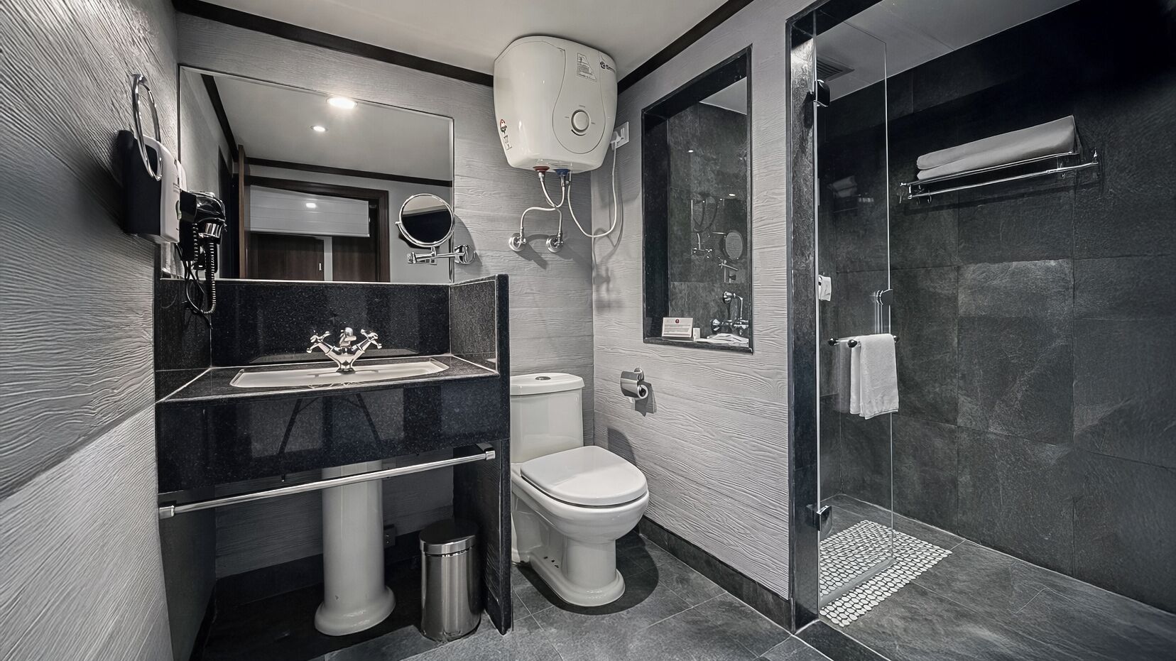 A modern bathroom with a glass-enclosed shower, a sink with a mirror, and a toilet.