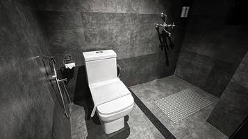 Un baño moderno con inodoro, ducha y barra de apoyo.