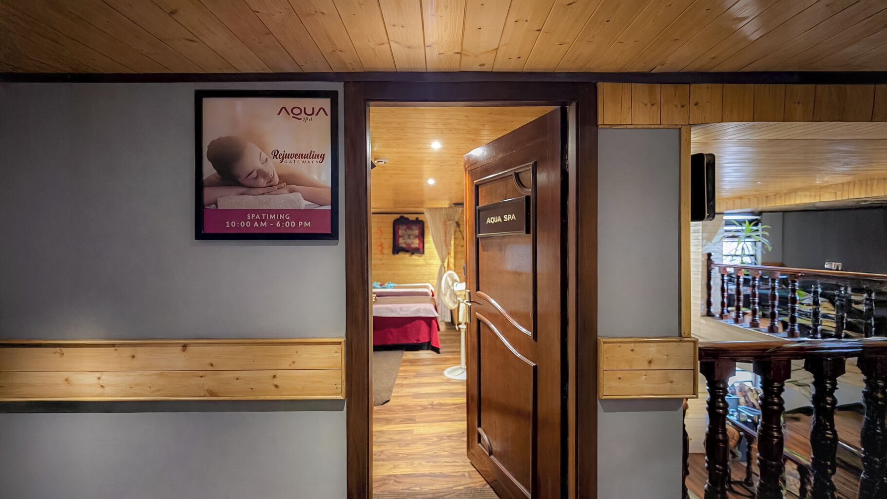 A wooden interior hallway leading to a spa area with a poster advertising Aqua Spa services.