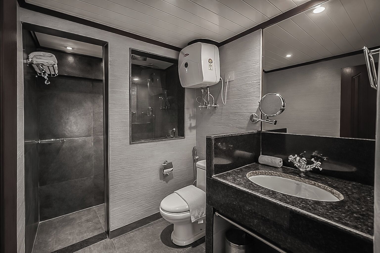 A modern bathroom with a walk-in shower, a toilet, a sink with a mirror, and a towel rack.