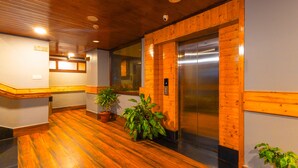 A wooden-floored lobby with an elevator and potted plants. - Sumitel Hotel 500 meters from Mall Road (Darjeeling)