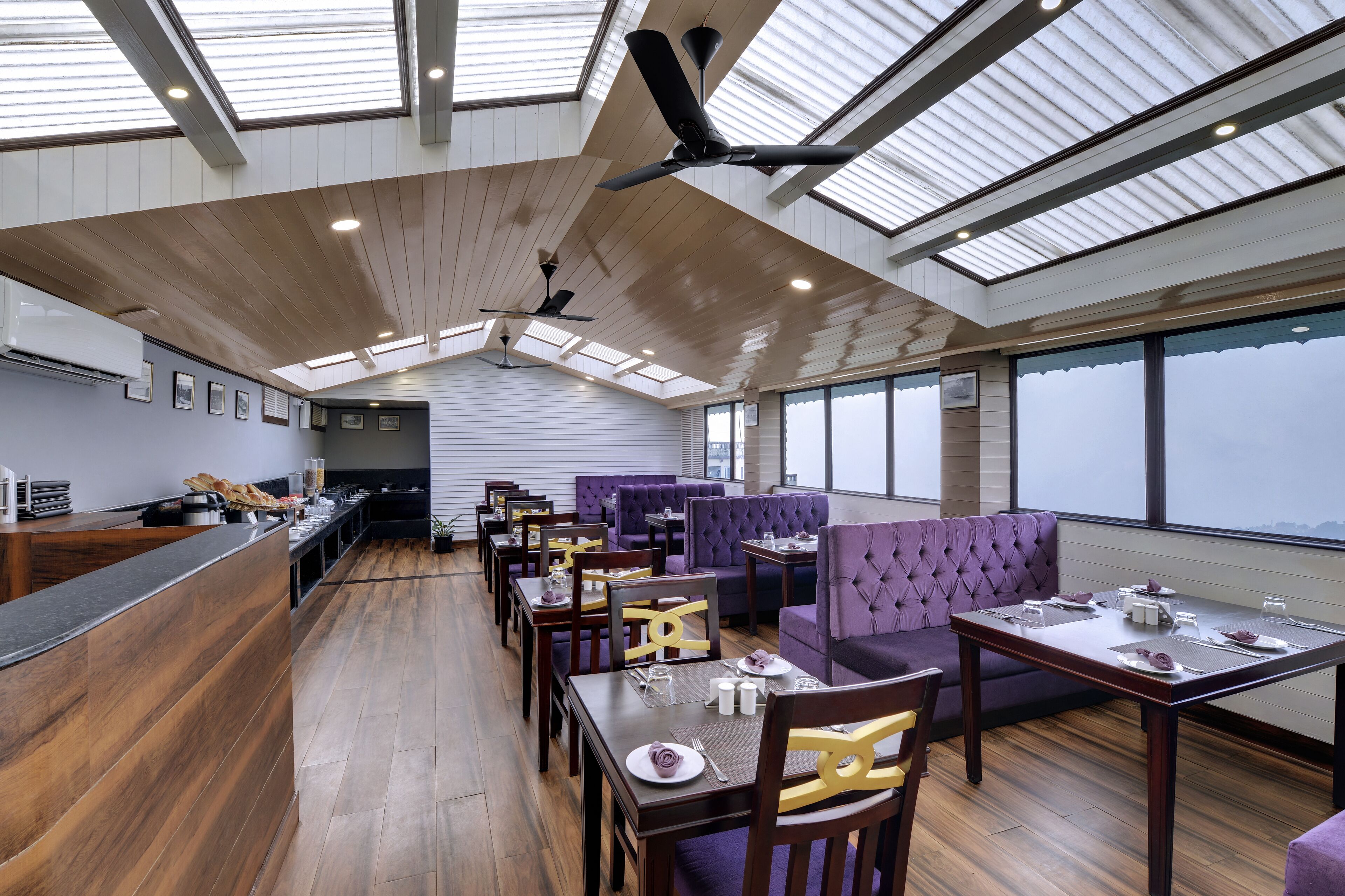 Un restaurante moderno con techos altos, tragaluces y una combinación de espacios para comer y zonas de estar.