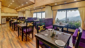 A restaurant with wooden floors, purple seating, and tables set for dining. - Sumitel Hotel 500 meters from Mall Road (Darjeeling)