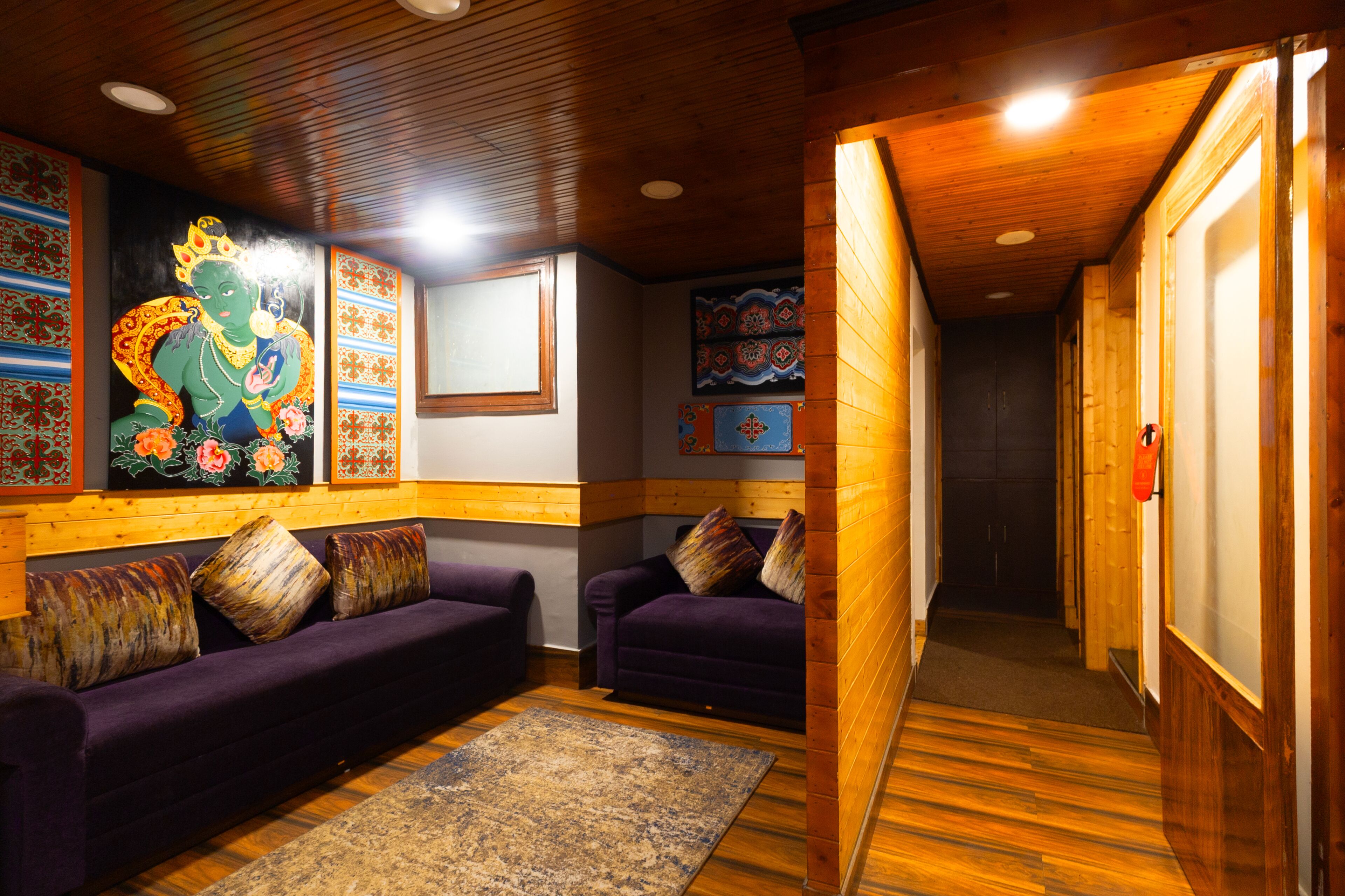 A room with wooden paneling, purple sofas, and a large mural on the wall.