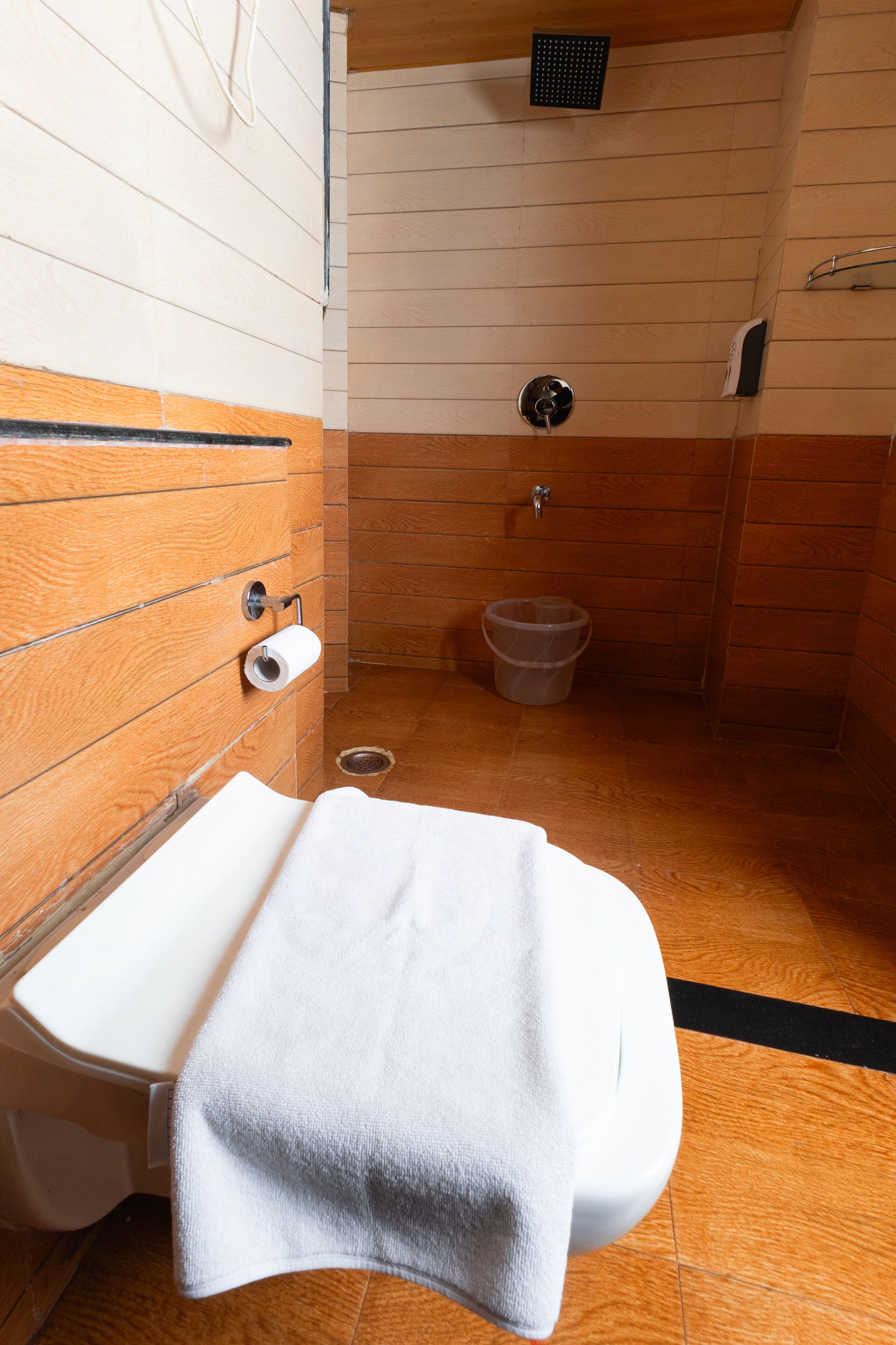 A bathroom with a wooden floor, a white sink, and a shower area.