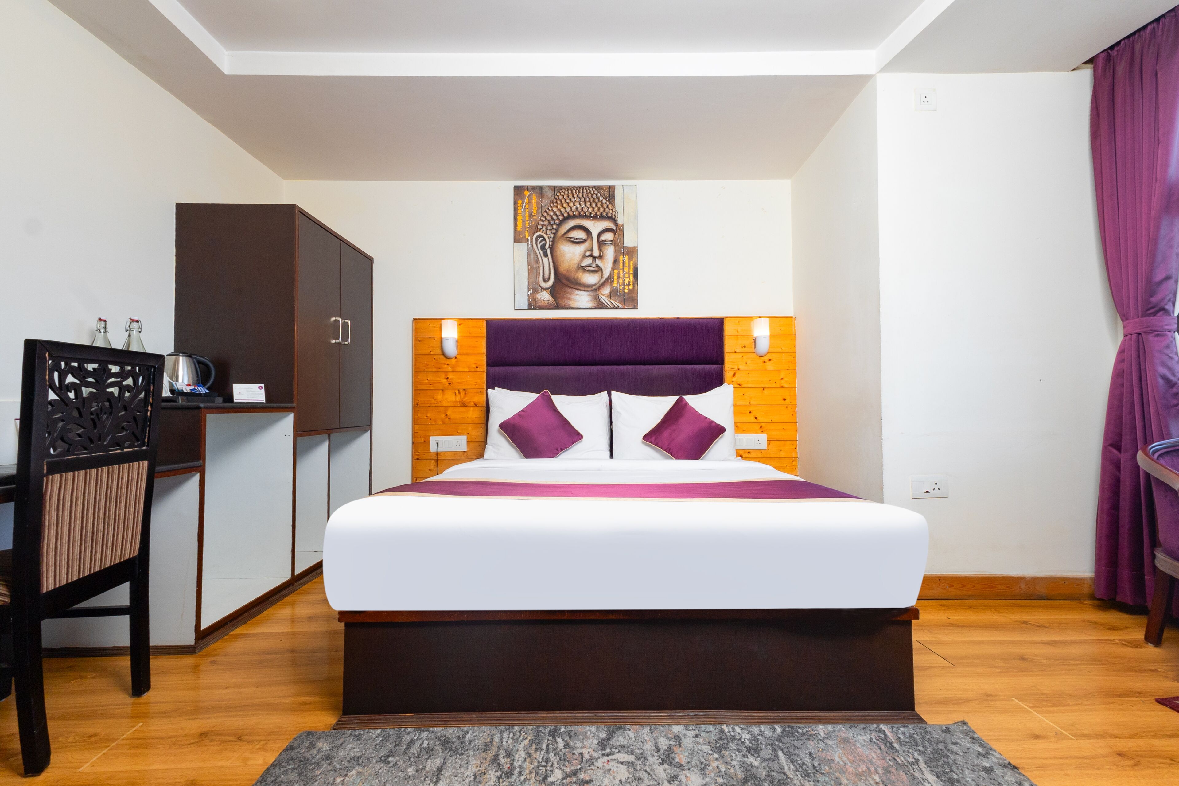 A bedroom with a large bed, wooden headboard, and a Buddha painting above it.