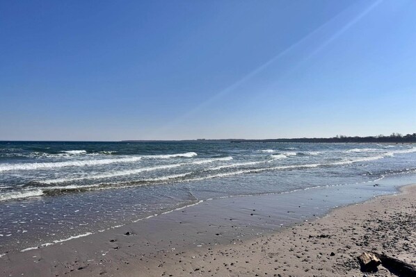 A beach with waves, a clear sky, and a distant shoreline.