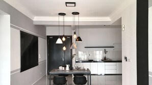 A modern kitchen with white cabinets, a black countertop, and pendant lighting. - Boulevard Service Apartment KL by Airhost (Kuala Lumpur)