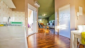 A kitchen with a sink, a green chair, and a white refrigerator.