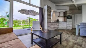 A modern living room with a sofa, a coffee table, and a dining area with a table and chairs. There is a large window providing a view of the outdoors. - 2 bedroom lovely home in Sint-Annaland (Sint-Annaland)