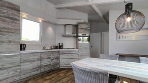 A modern kitchen with a large island, built-in appliances, and a dining area with wicker chairs. - 2 bedroom lovely home in Sint-Annaland (Sint-Annaland)