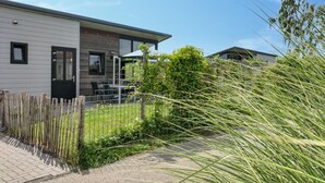A modern two-story house with a patio, a wooden fence, and a grassy yard. - 2 bedroom lovely home in Sint-Annaland (Sint-Annaland)