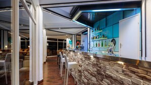 Una zona de bar con mostrador de piedra, taburetes y vista al comedor.