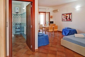Una habitación con una cama, una pequeña mesa con sillas y un baño visible a través de una puerta abierta.