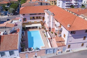 Un edificio residencial con piscina, balcones y techo de tejas.
