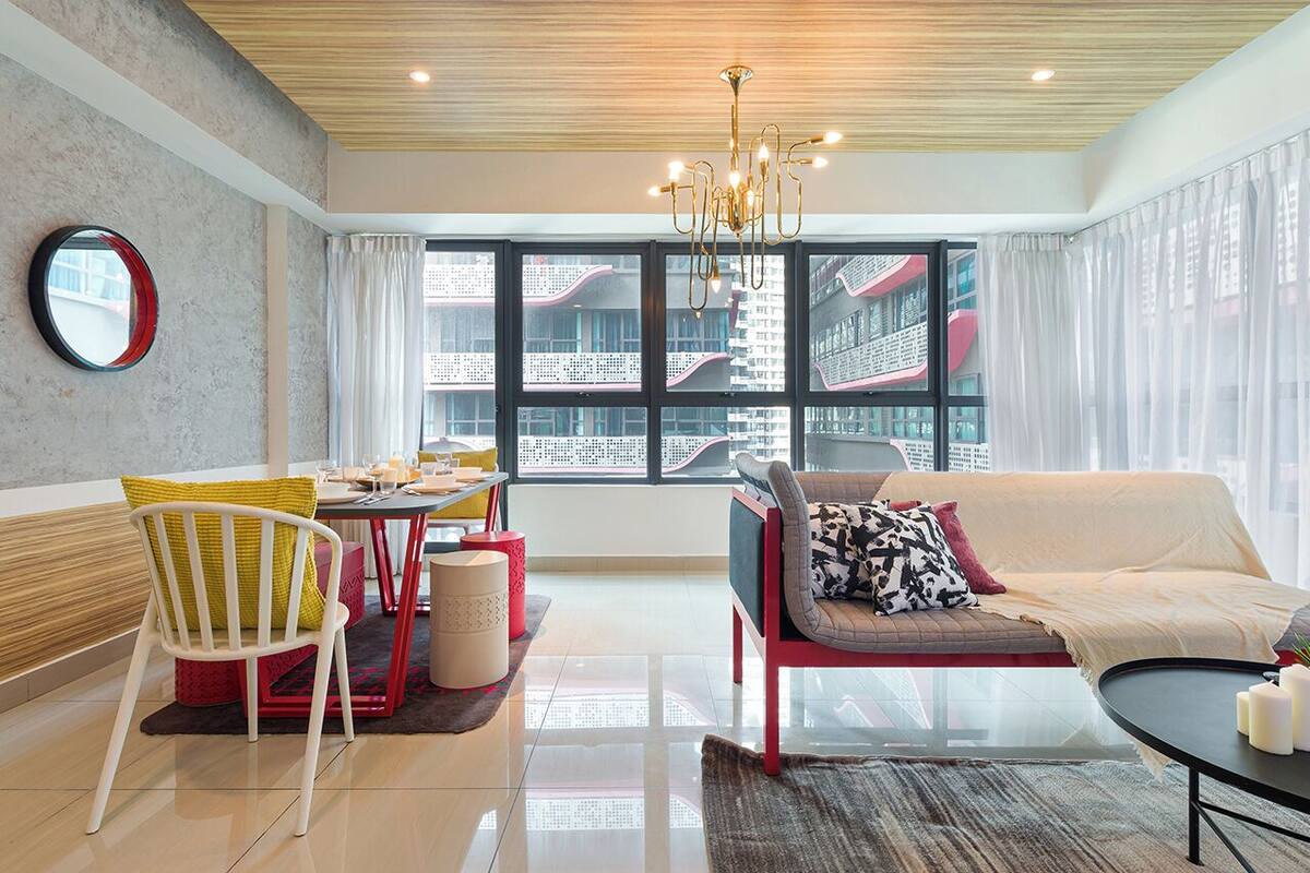 A modern living room with a sofa, a dining table, and a large window with a city view.