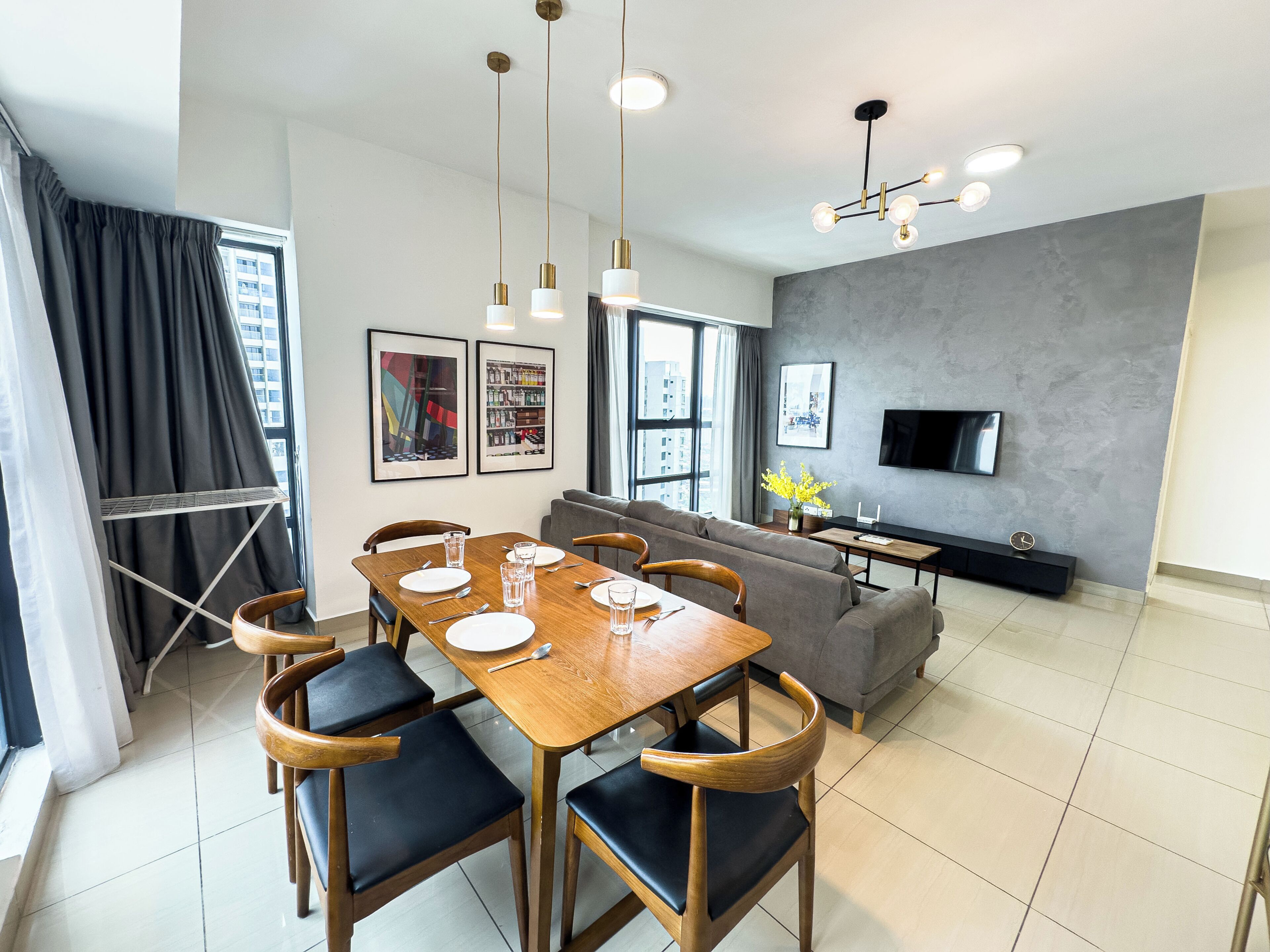 Een moderne woonkamer met een eethoek, een grijze bank, een flatscreen-televisie en kunstwerken aan de wanden.