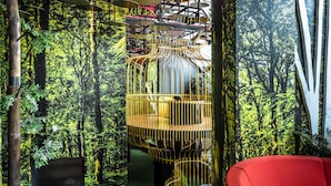 Ein modernes Interieur mit einem roten Sofa, einer außergewöhnlichen Wendeltreppe und einer Wand mit Waldmotiv.