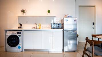 Cocina compacta equipada con lavadora, refrigerador, microondas y pileta.