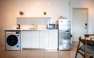 Cocina compacta equipada con lavadora, refrigerador, microondas y pileta.