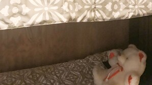 Una cama con un edredón estampado, un oso de peluche blanco y un objeto rojo sobre la cama.