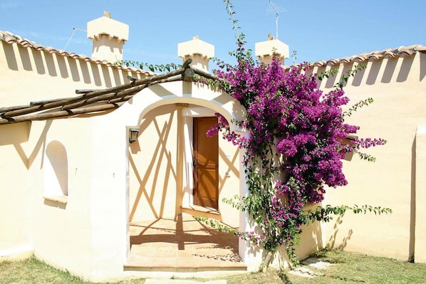 A building with a beige facade, a wooden door, and a small archway.