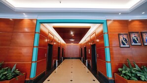 Un pasillo de hotel con paredes de madera, suelo de baldosas y cuadros enmarcados a la derecha.