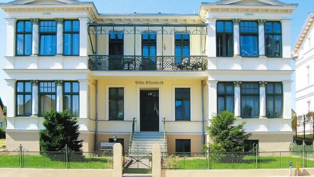 A two-story building with a classical architectural style, featuring a central entrance with steps and a balcony on the upper floor. - Ferienwohnung Meeresrausch in Ahlbeck (Ahlbeck)