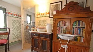 A kitchen with a wooden cabinet, a white sink, and a bookshelf filled with books. - Ferienwohnung Meeresrausch in Ahlbeck (Ahlbeck)
