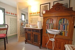 Una cocina con un armario de madera, un lavamanos blanco y una estantería llena de libros.