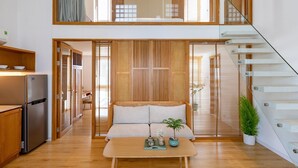 A modern kitchen with a built-in refrigerator, wooden flooring, and a dining area with a table and chairs.