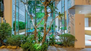 A modern building with a glass facade, indoor plants, and a seating area.