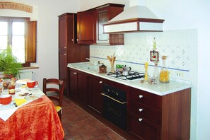 Una cocina con armarios de madera, una estufa y una mesa de comedor preparada para una comida.