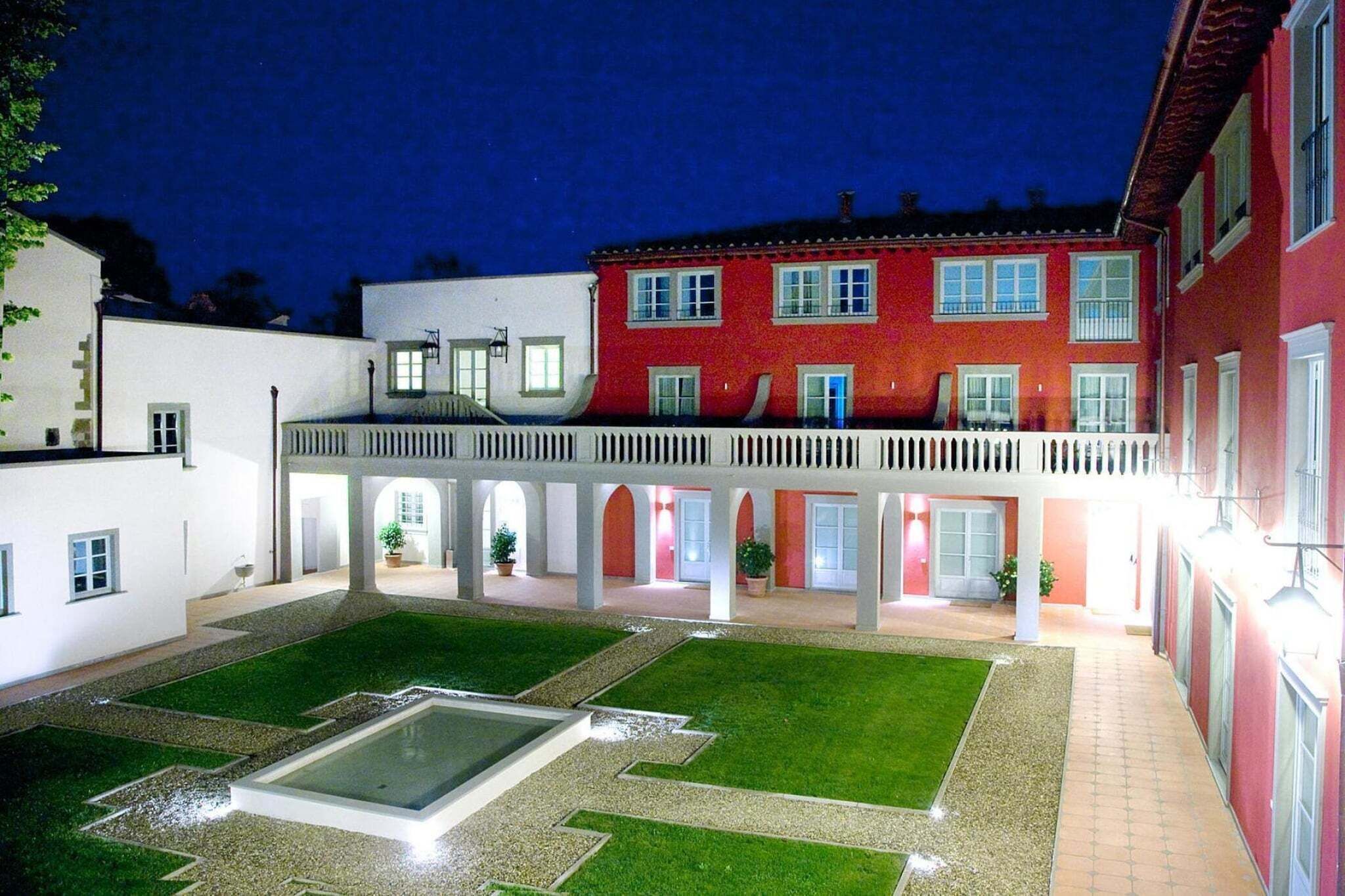 Un patio con piscina, un paseo cubierto y edificios con amplias ventanas.