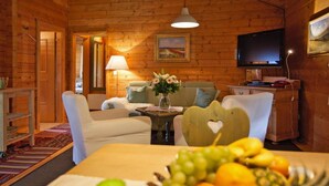 A cozy cabin interior with a wooden interior, a television, a dining table with fruit, and a sofa. - Blockhäuser in Stamsried (Stamsried)