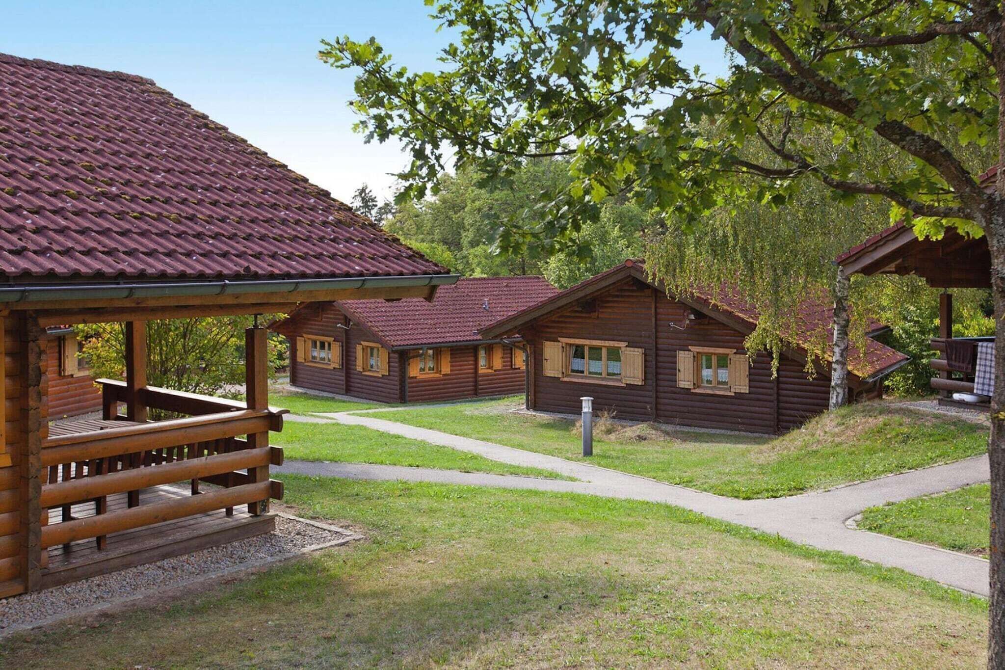 A row of wooden cabins with a covered porch and a paved walkway.