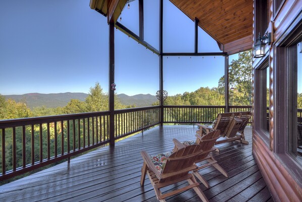 A wooden deck with Adirondack chairs, a wooden railing, and a view of mountains. - Fraggle Rock - Blue Ridge (Mineral Bluff)