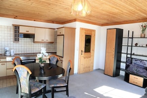 Cozy room with a dining area, kitchenette, and entertainment unit.