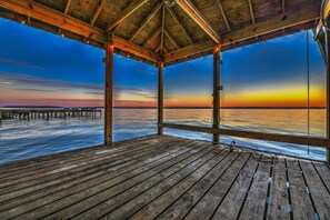 A wooden deck with a view of the ocean at sunset. - Beautiful Lake Front home for memories to last a lifetime! (Livingston)