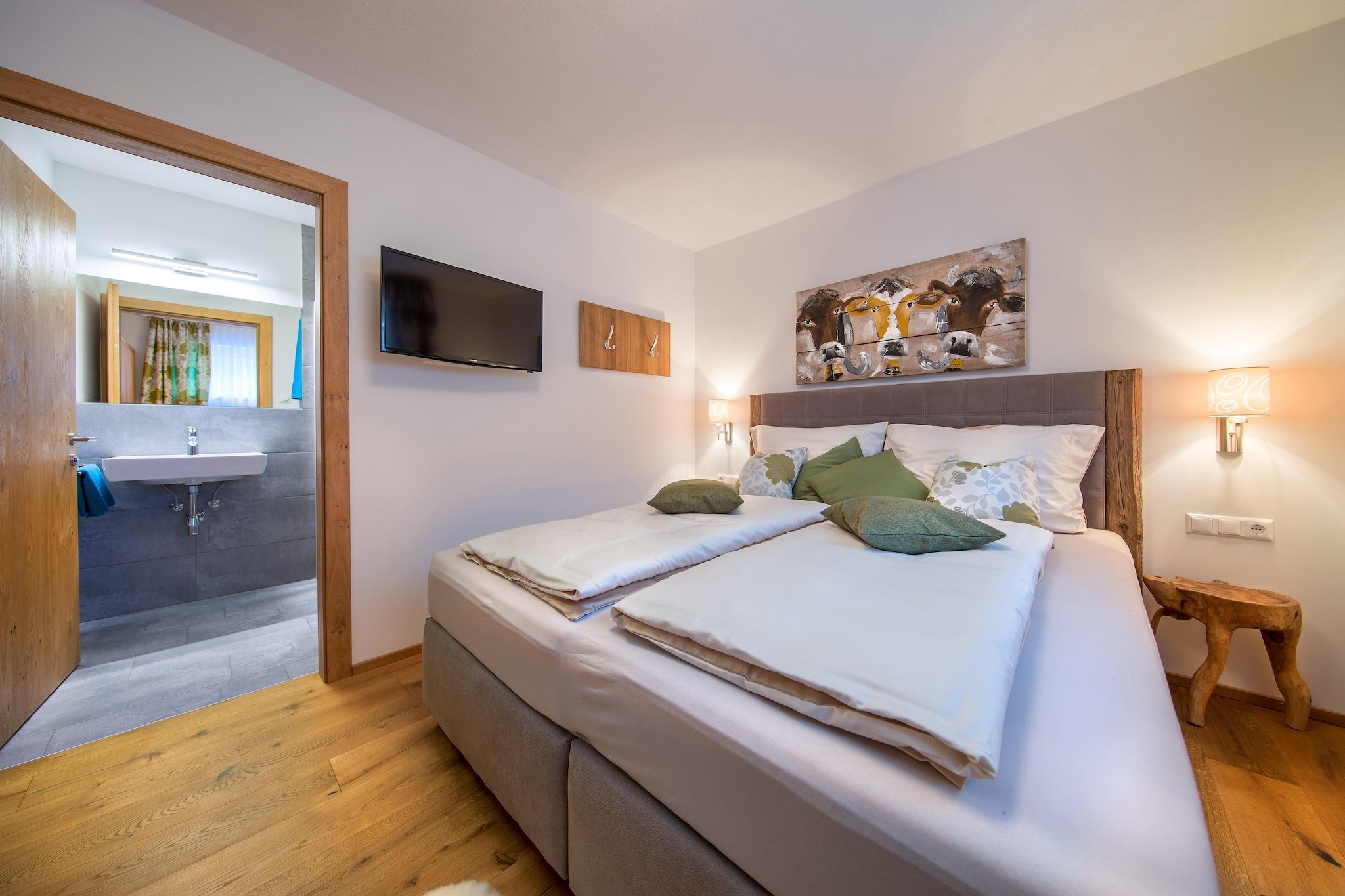 Une chambre à coucher avec un lit, une télévision, un tableau et une lampe de chevet.