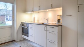 A modern kitchen with white cabinets, a stainless steel oven, and a coffee maker. - 1 bedroom cozy home in Grindsted (Grindsted)